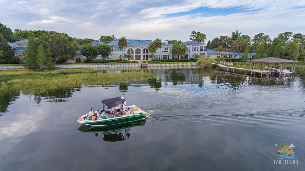 Boat cruising past a lakefront estate and boathouse on the Butler Chain of Lakes