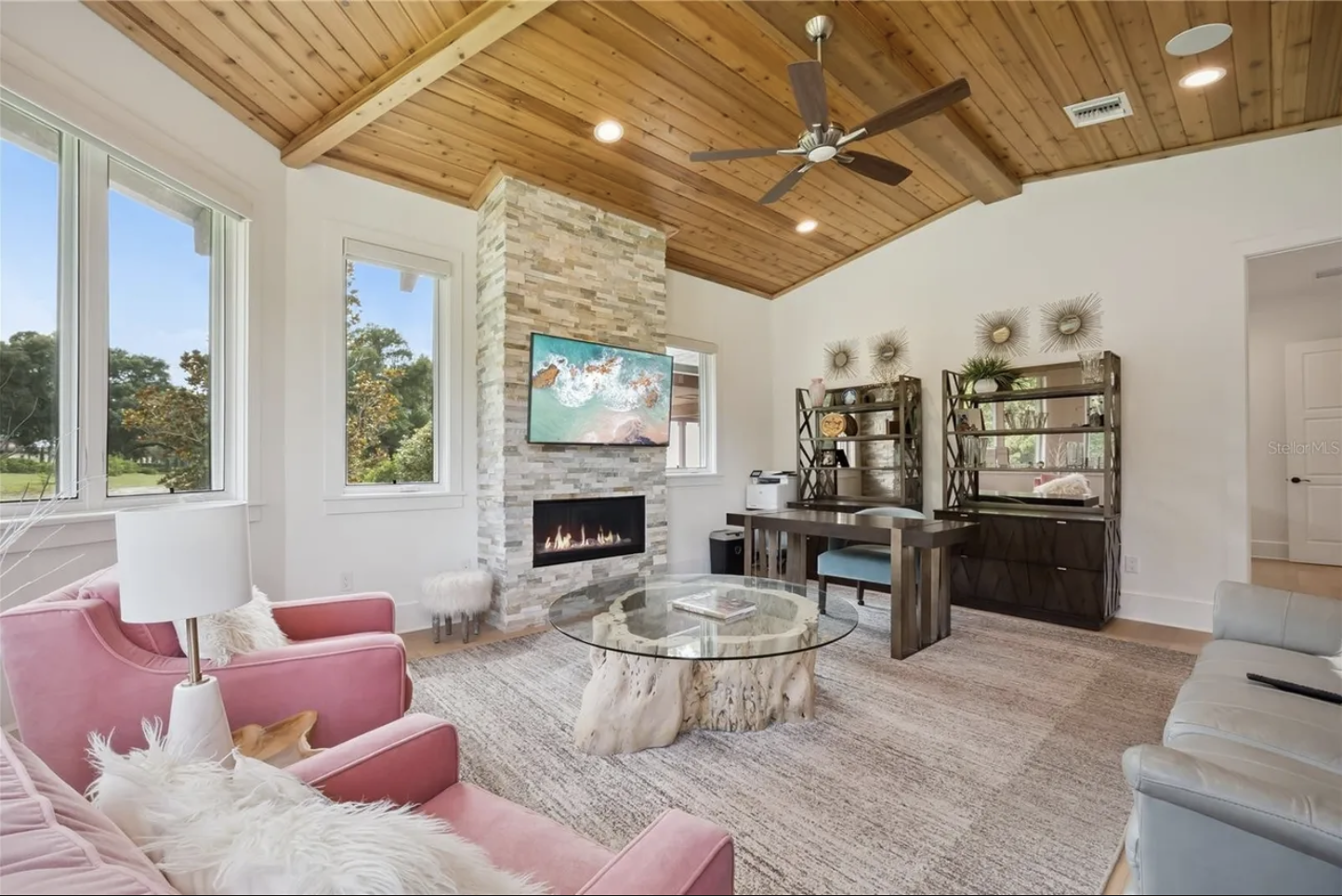Sitting room with stone fireplace and vaulted wood ceiling